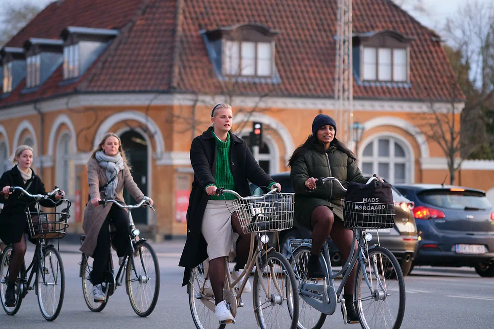 Group of cyclists passing an old yellow brick building at Frederiksberg