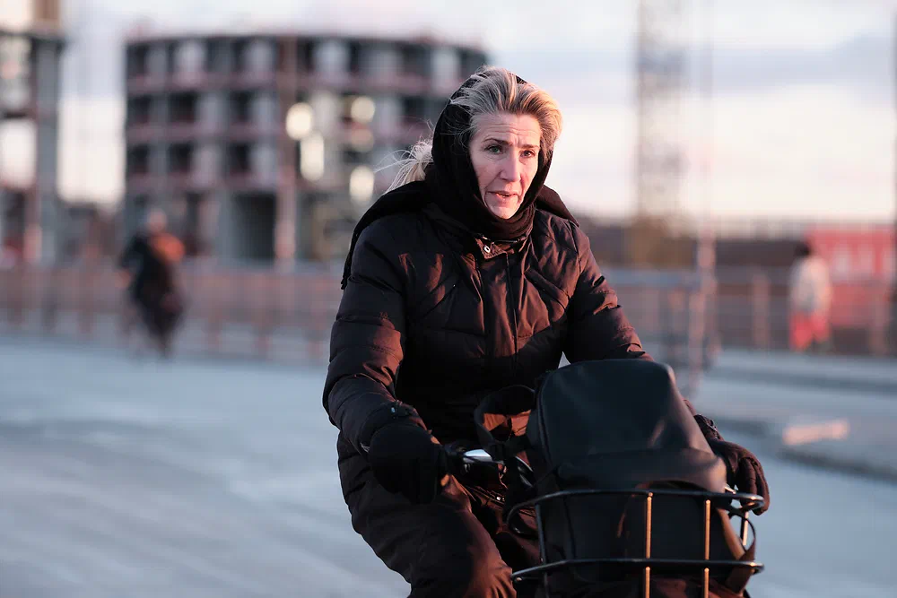 Woman with a scarf over her head cycling near Dybbølsbro in winter