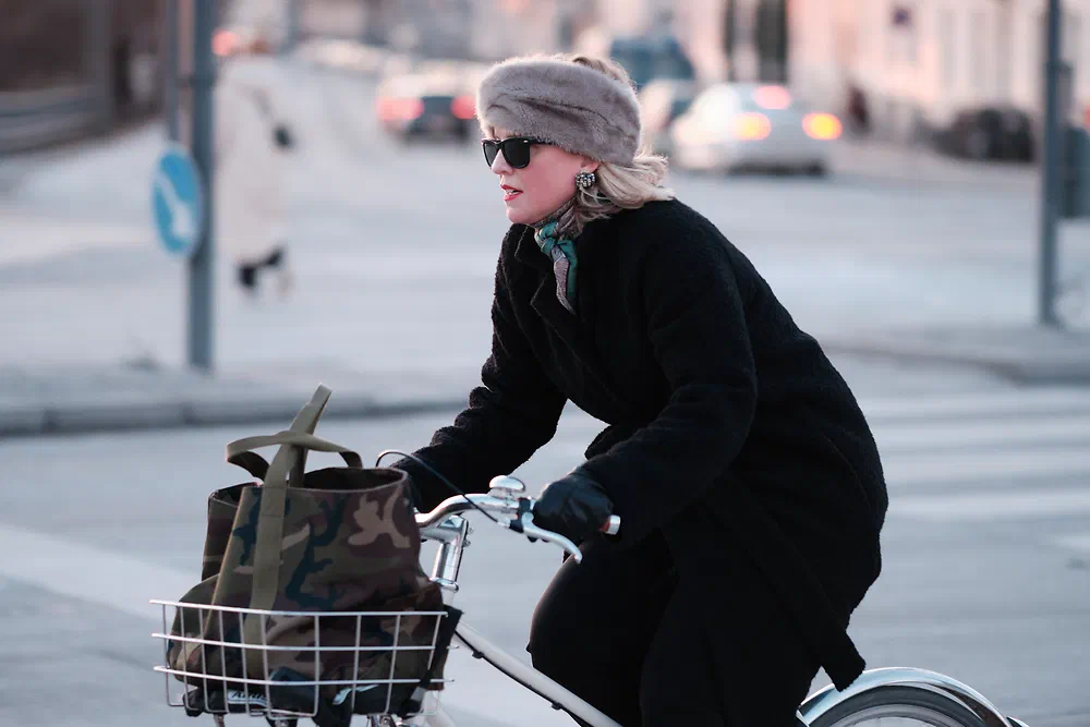 Woman in a knitted hat and sunglasses cycling near Dybbølsbro in winter
