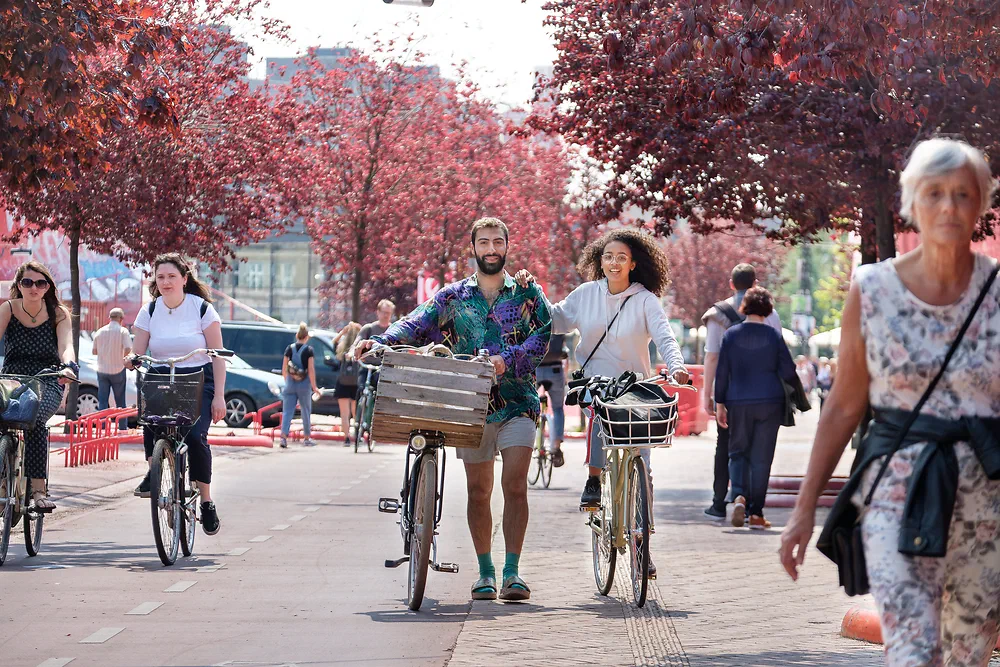 Cyclists and pedestrians on the red surface of the Red Square at Nørrebro under red-leaved trees