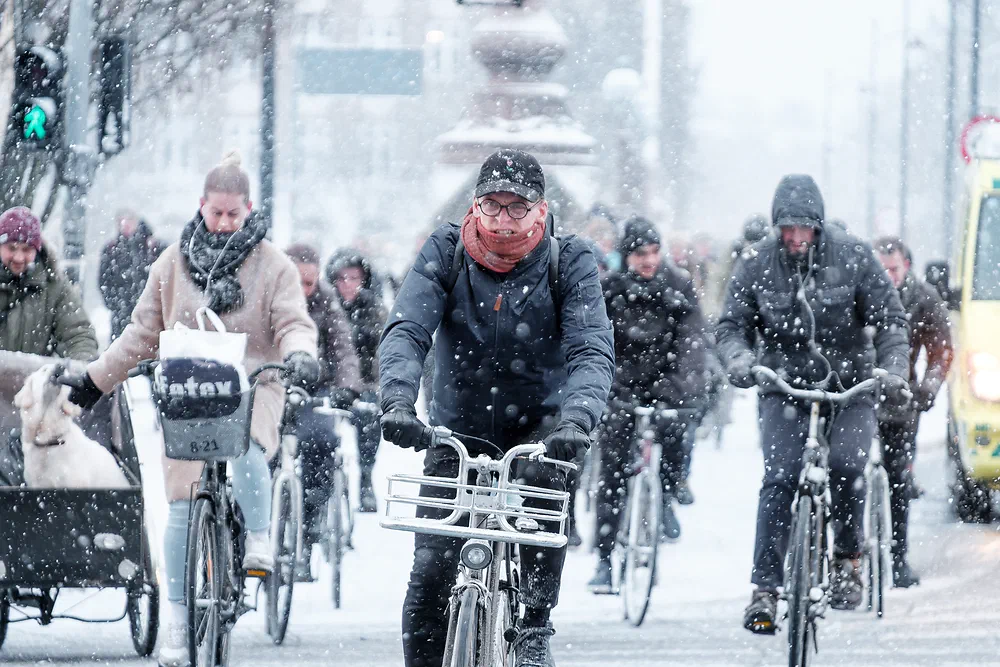 Cyclists riding through heavy snowfall on Dronning Louises Bro in Copenhagen