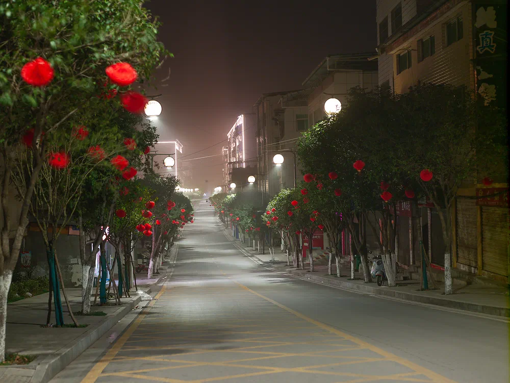 Night street in Yunxi lined with trees decorated with red lanterns for Chinese New Year