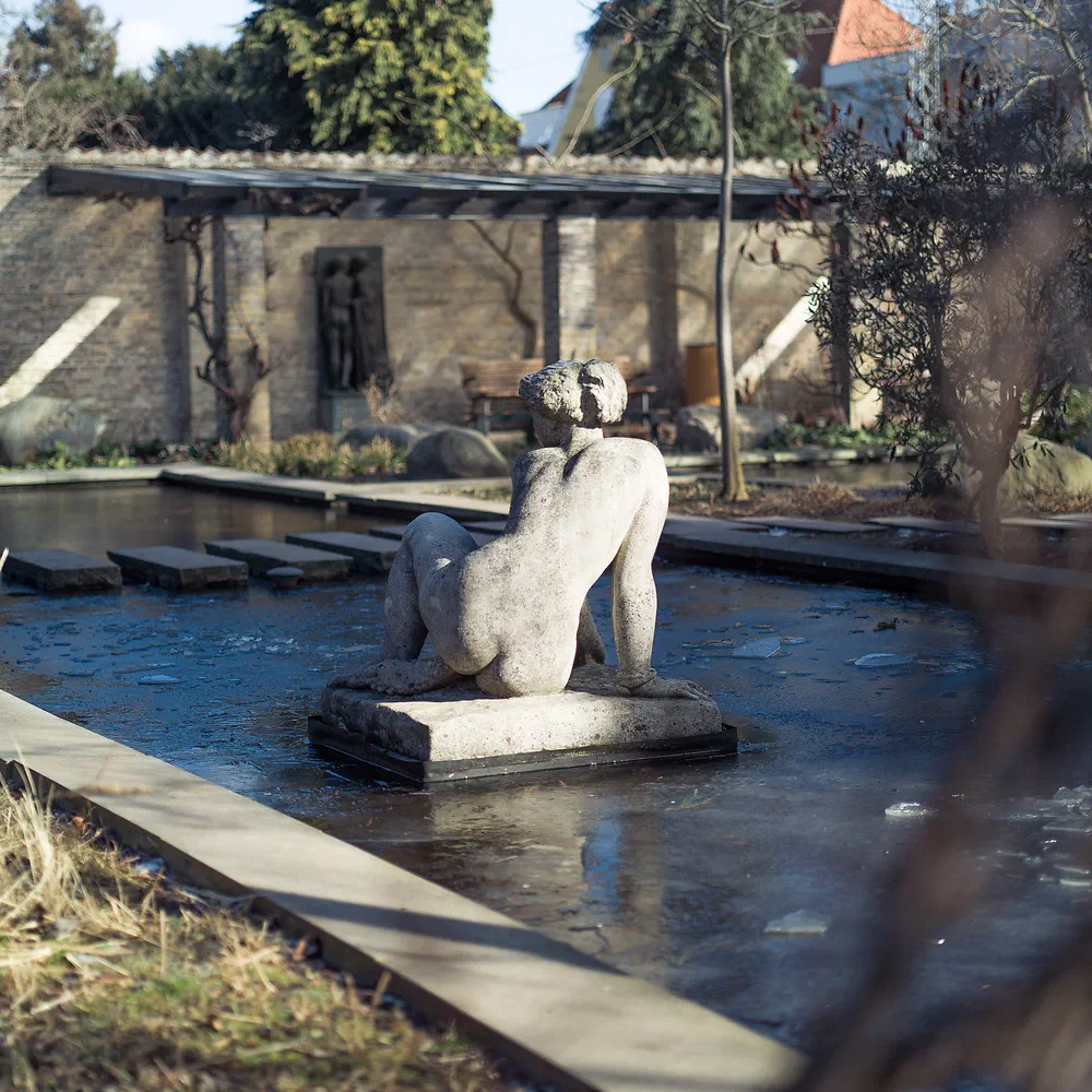 Sculpture of a reclining figure in a pond at Haveselskabets Have, Frederiksberg
