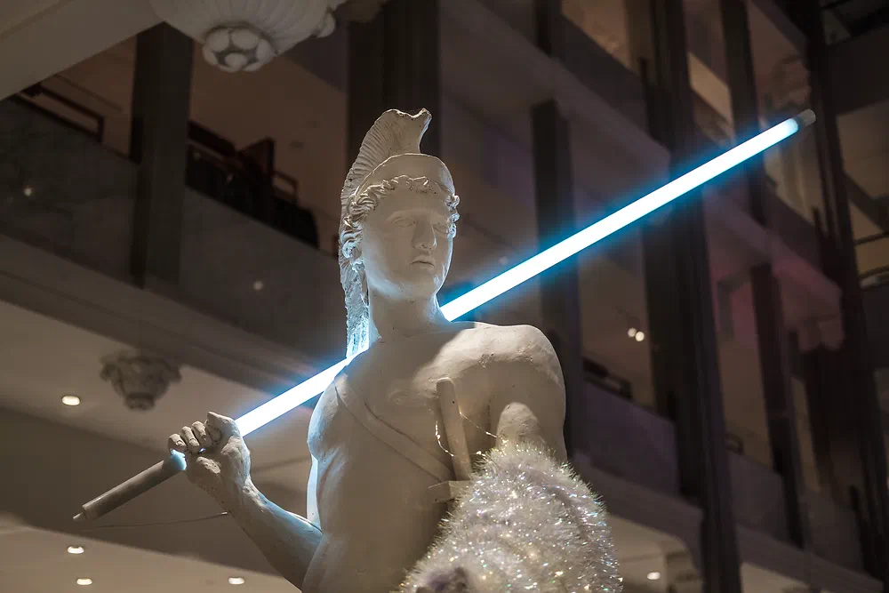 Statue of a warrior holding a glowing light tube like a lightsaber inside Magazin in Copenhagen