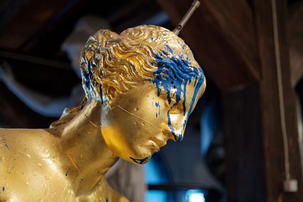 Gold painted plaster head with blue paint dripping down