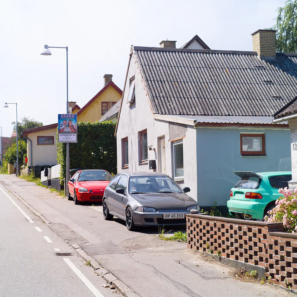 Three Honda Civics in red, grey and turquoise parked in front of a small house in Lumsås