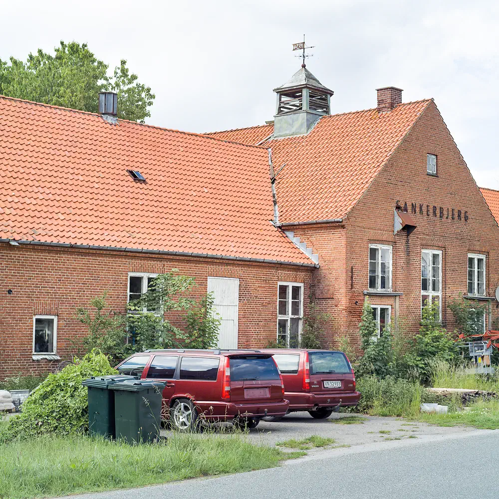 Old red brick dairy building Sankerbjerg Andelsmejeri in Egebjerg with two red Volvo V70 station wagons