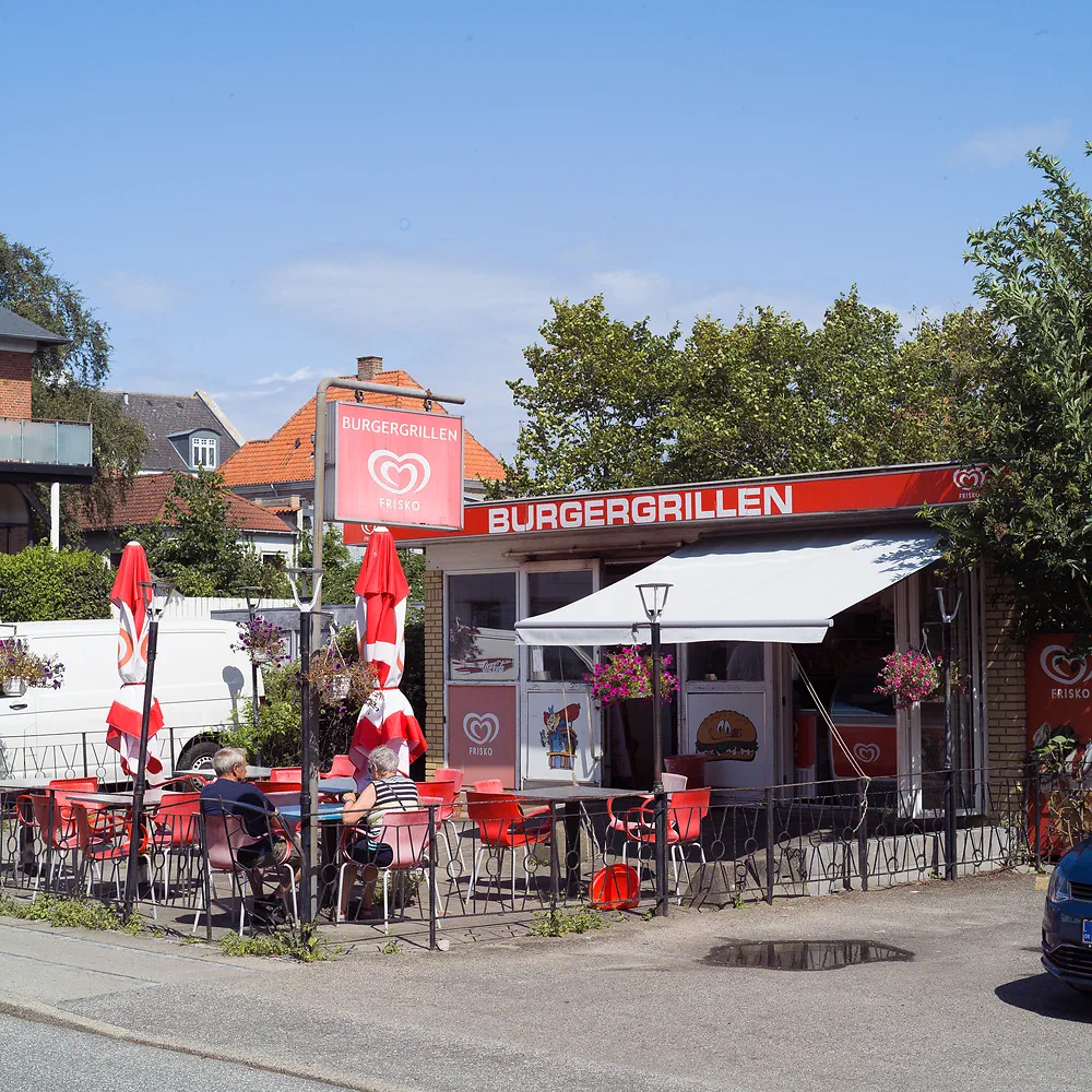 Burgergrillen snack bar in Nykøbing Sjælland with red parasols and people sitting outside
