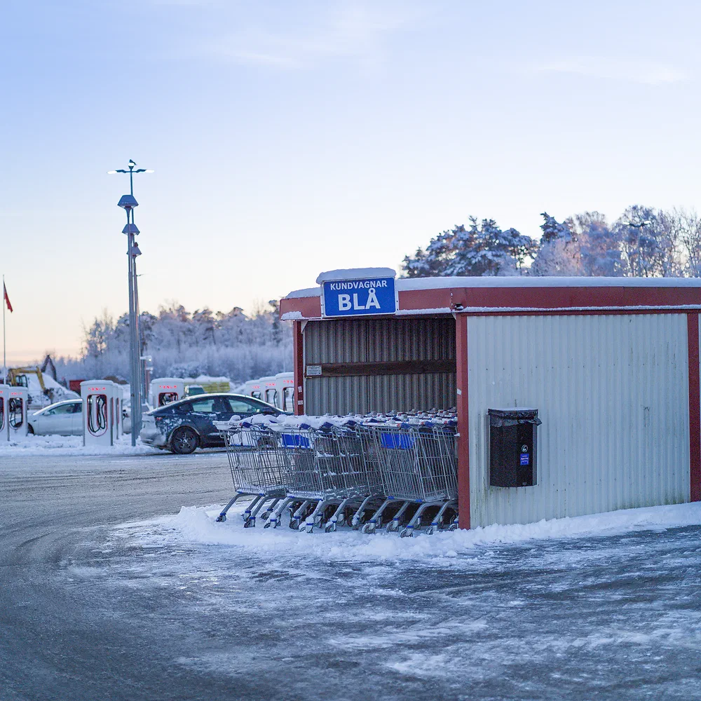 Shopping cart shelter in a snowy parking lot at dusk