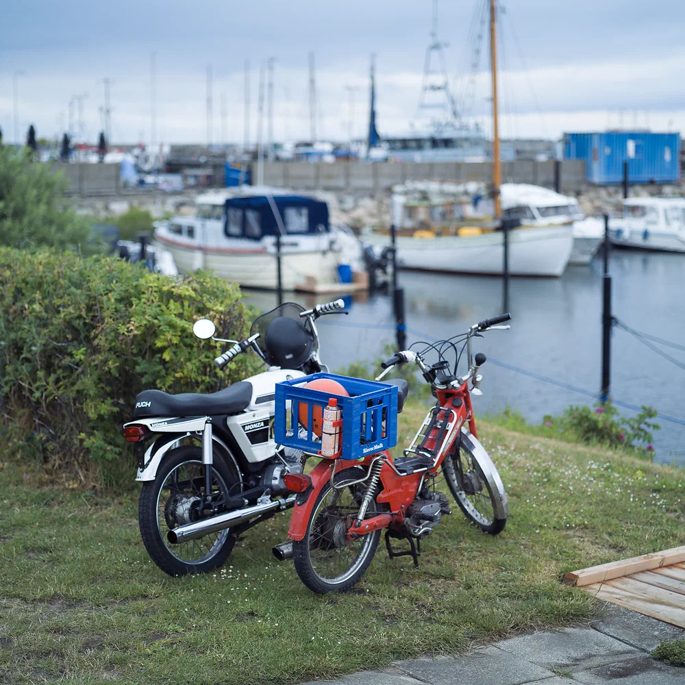 Two old Puch Maxi mopeds parked on the grass by the harbour in Havnebyen