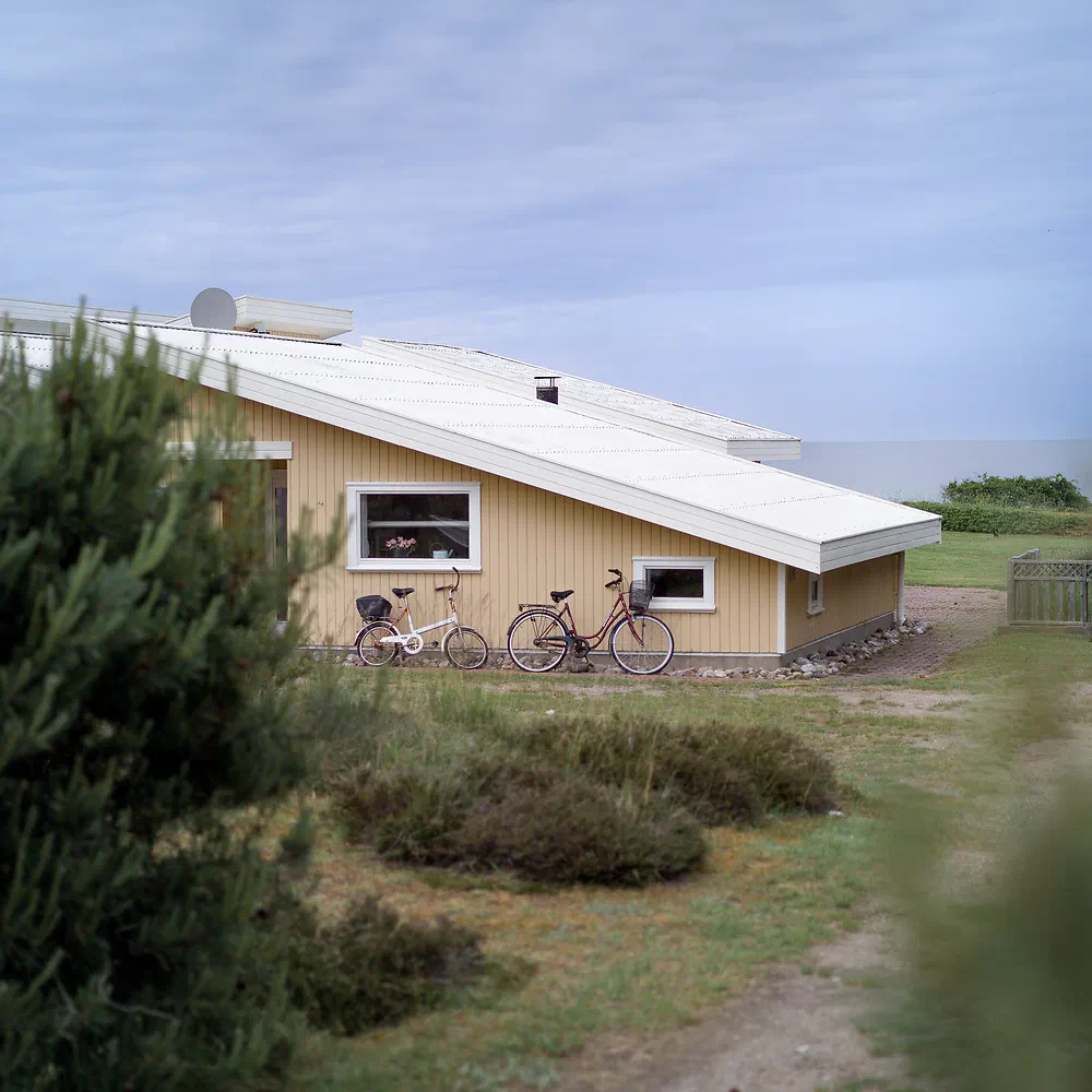 Yellow summer house with a white roof and bicycles by the coast