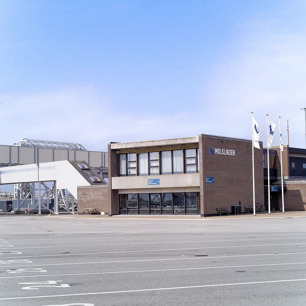 Molslinjen ferry terminal building with flags and an empty car park at Sjællands Odde