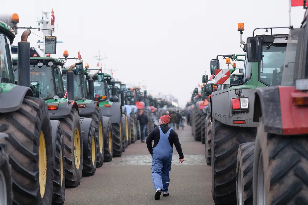 Farmer walking between two long rows of tractors at a demonstration in Copenhagen
