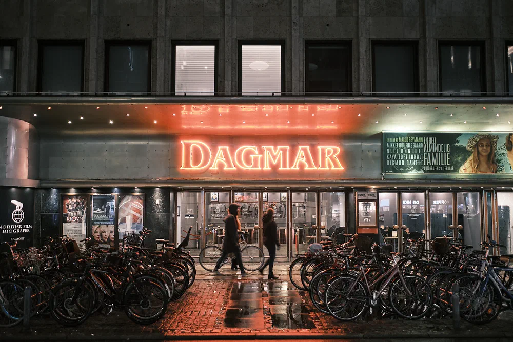 Neon sign of Dagmar Cinema in Copenhagen at night with bicycles parked in front