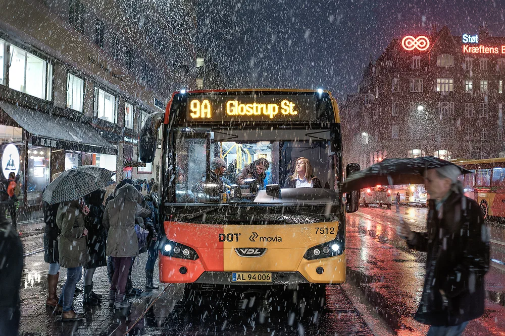 City bus 9A to Glostrup at Christianshavn in falling snow with people waiting under umbrellas