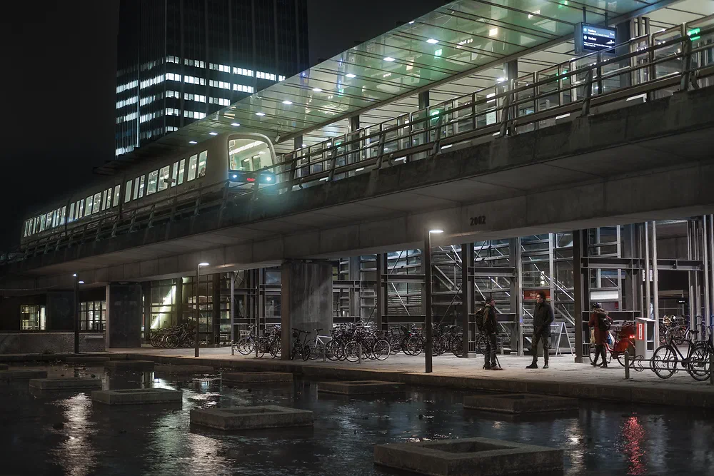 Elevated Ørestad metro station in Copenhagen at night reflected in the water below