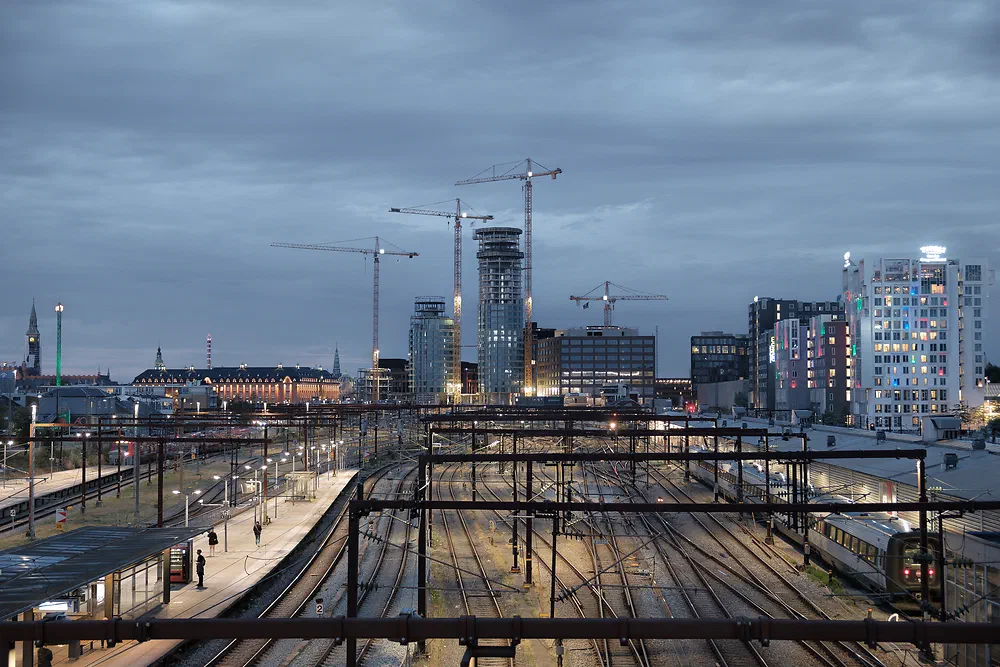Railway tracks seen from Dybbølsbro at dusk with cranes and new towers being built in Postbyen, Copenhagen
